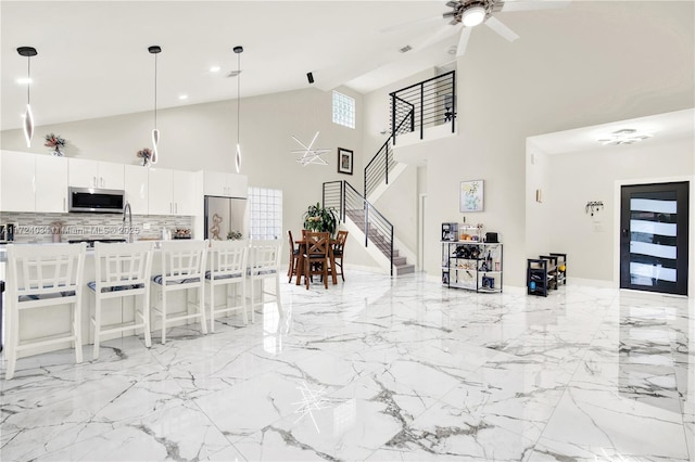 kitchen featuring white cabinetry, a kitchen breakfast bar, backsplash, pendant lighting, and appliances with stainless steel finishes