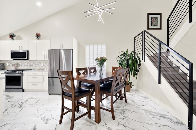 dining area featuring an inviting chandelier and high vaulted ceiling