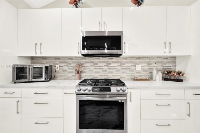 kitchen featuring white cabinets, light stone counters, stainless steel appliances, and tasteful backsplash