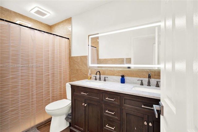 bathroom with curtained shower, vanity, tile walls, and toilet