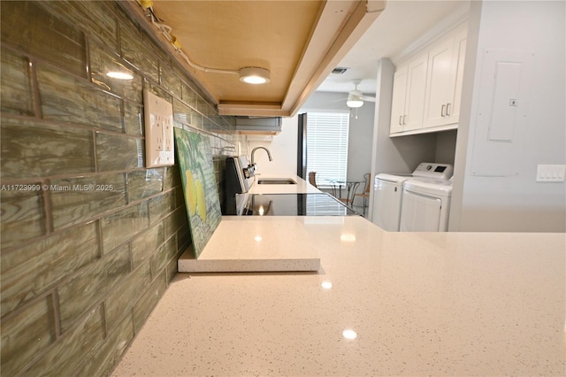 kitchen with white cabinetry, sink, and washing machine and clothes dryer