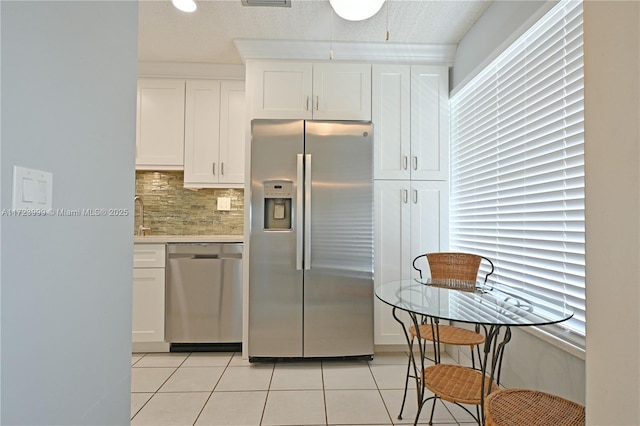 kitchen with white cabinets, light tile patterned floors, appliances with stainless steel finishes, and tasteful backsplash