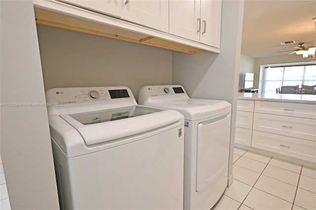 clothes washing area with separate washer and dryer, ceiling fan, light tile patterned floors, and cabinets