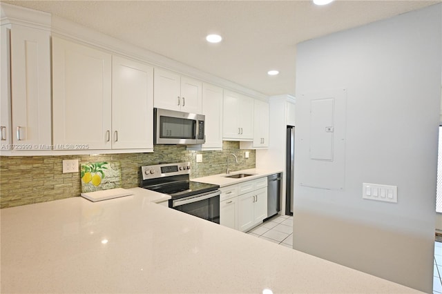 kitchen featuring backsplash, white cabinets, sink, light tile patterned floors, and appliances with stainless steel finishes