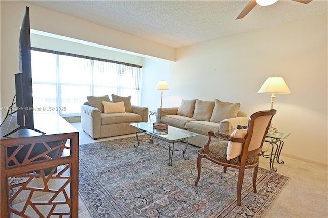 carpeted living room featuring ceiling fan and a textured ceiling