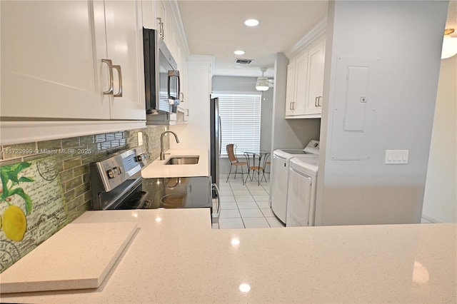 kitchen featuring light tile patterned flooring, sink, electric range oven, white cabinetry, and washing machine and clothes dryer