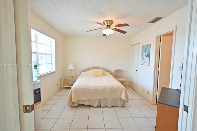 tiled bedroom with ceiling fan and a textured ceiling