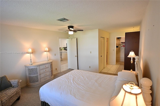 bedroom with ceiling fan, light colored carpet, and a textured ceiling