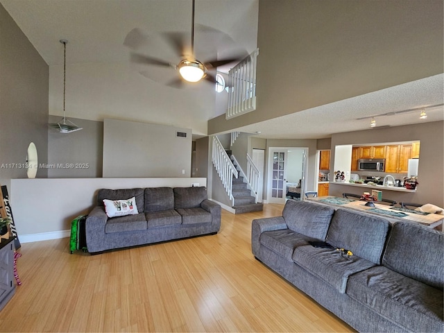 living room with ceiling fan, light hardwood / wood-style flooring, and high vaulted ceiling