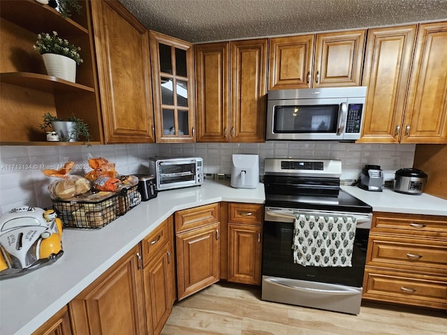 kitchen with backsplash, light hardwood / wood-style flooring, and appliances with stainless steel finishes