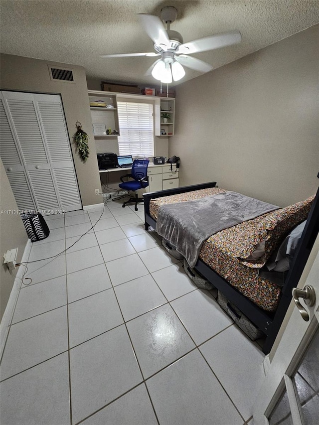 bedroom with light tile patterned floors, a textured ceiling, a closet, and ceiling fan