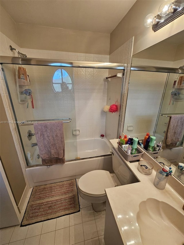 full bathroom featuring toilet, vanity, tile patterned floors, and bath / shower combo with glass door