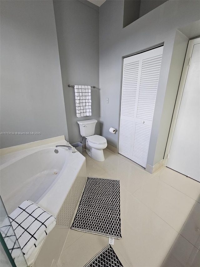 bathroom with tile patterned floors, toilet, and a bath