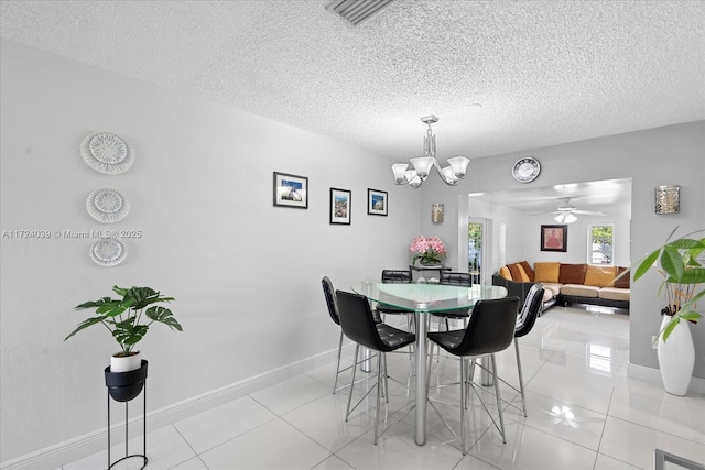 tiled dining room with a textured ceiling and ceiling fan with notable chandelier