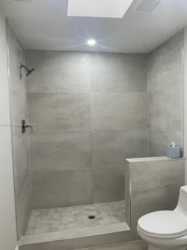 bathroom featuring a tile shower and toilet