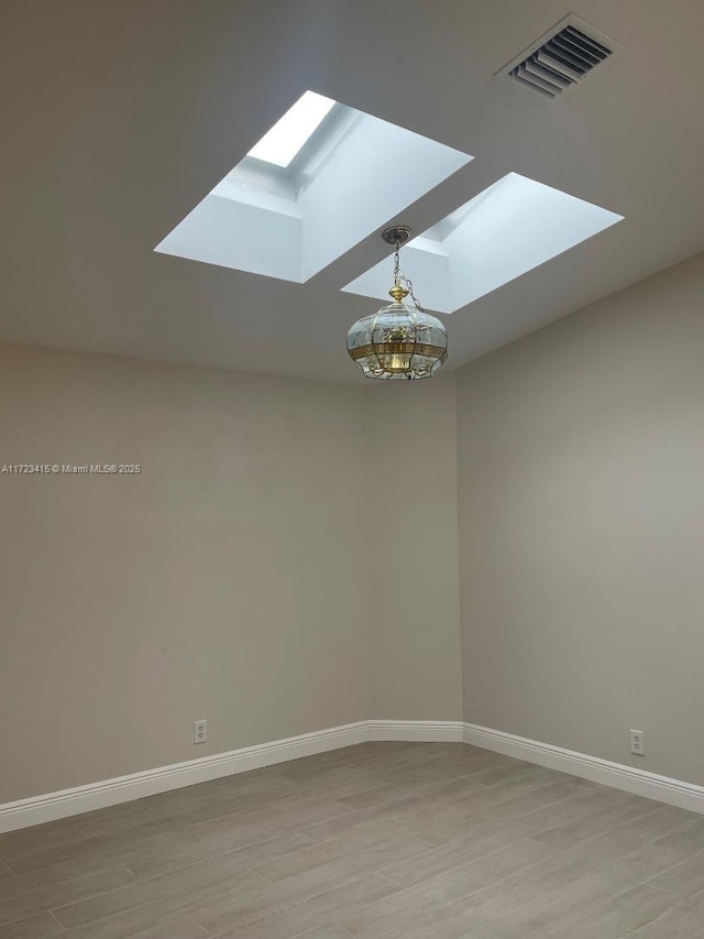 unfurnished room with light hardwood / wood-style floors and a skylight