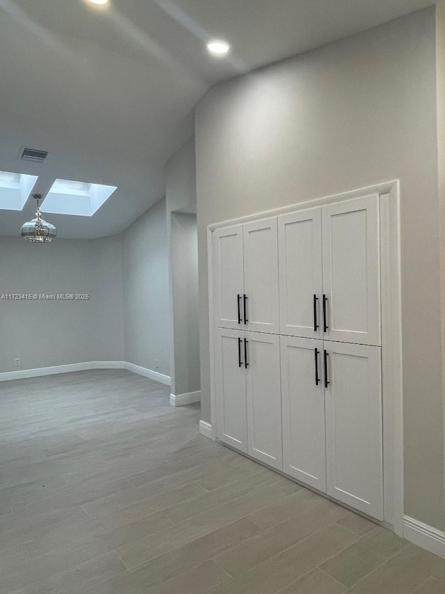 bonus room featuring vaulted ceiling with skylight and light hardwood / wood-style flooring