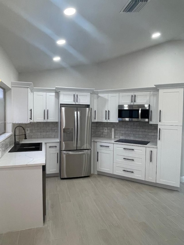 kitchen with backsplash, sink, white cabinets, and stainless steel appliances