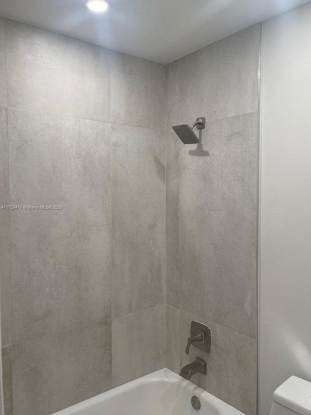 bathroom with tiled shower / bath combo and toilet