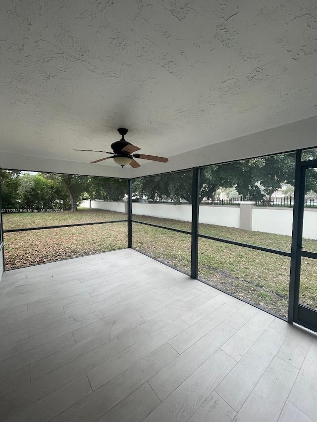 unfurnished sunroom with ceiling fan