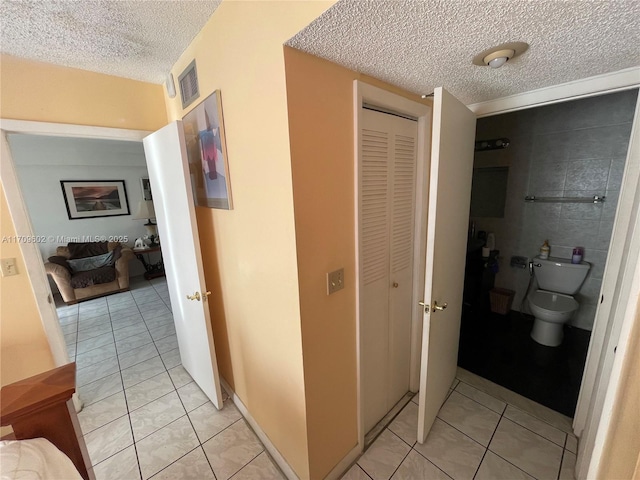 hallway with light tile patterned flooring and a textured ceiling