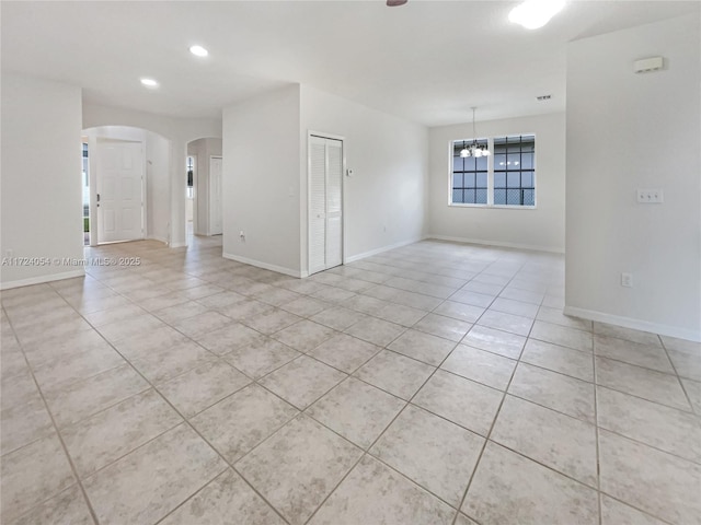 tiled empty room featuring a chandelier