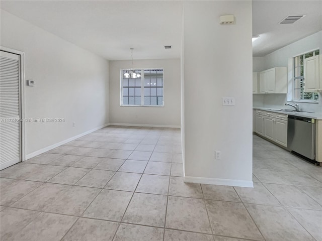 empty room featuring light tile patterned floors, a notable chandelier, and sink