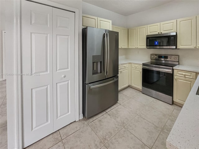 kitchen with cream cabinets, stainless steel appliances, and light tile patterned floors