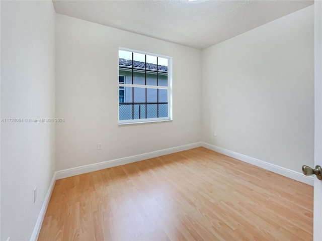 spare room with a textured ceiling and light wood-type flooring