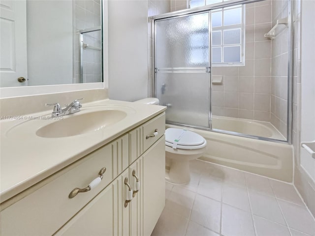 full bathroom featuring toilet, vanity, tile patterned floors, and bath / shower combo with glass door