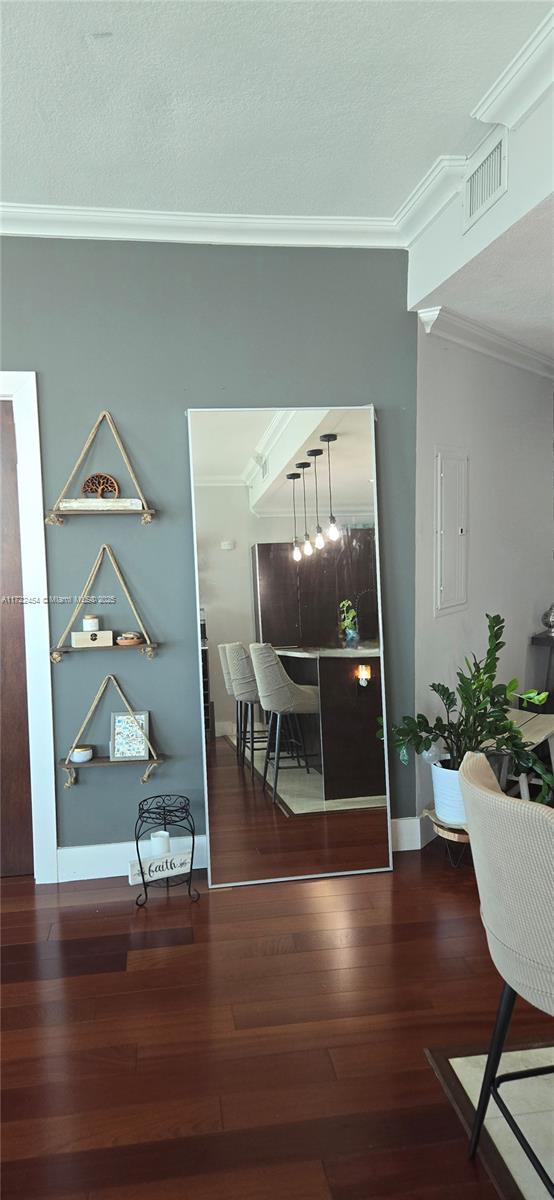 hallway with hardwood / wood-style flooring, ornamental molding, and electric panel