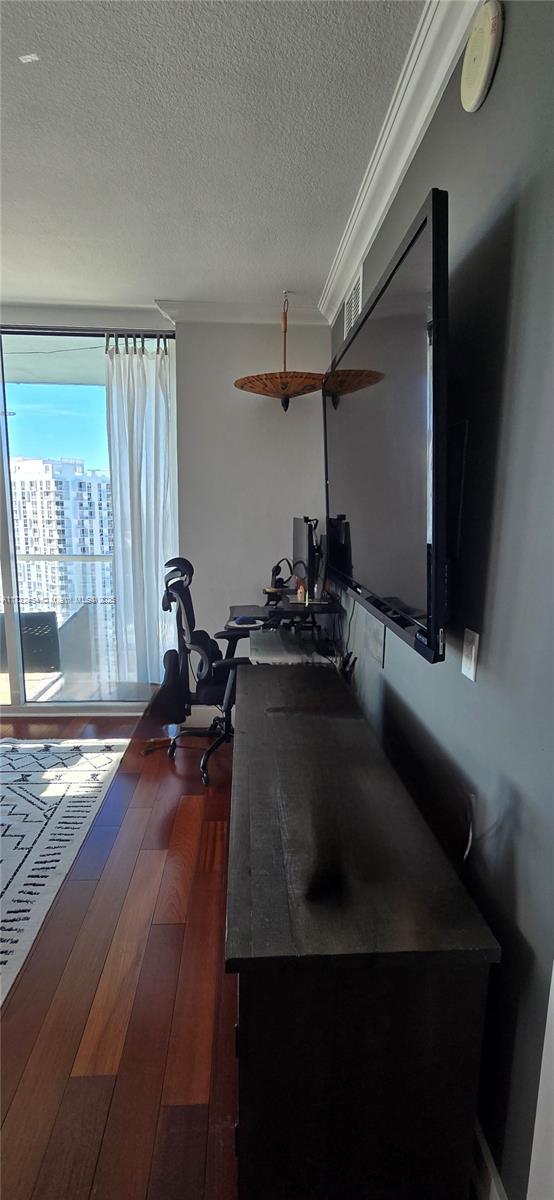 exercise area with dark hardwood / wood-style flooring, crown molding, and a textured ceiling