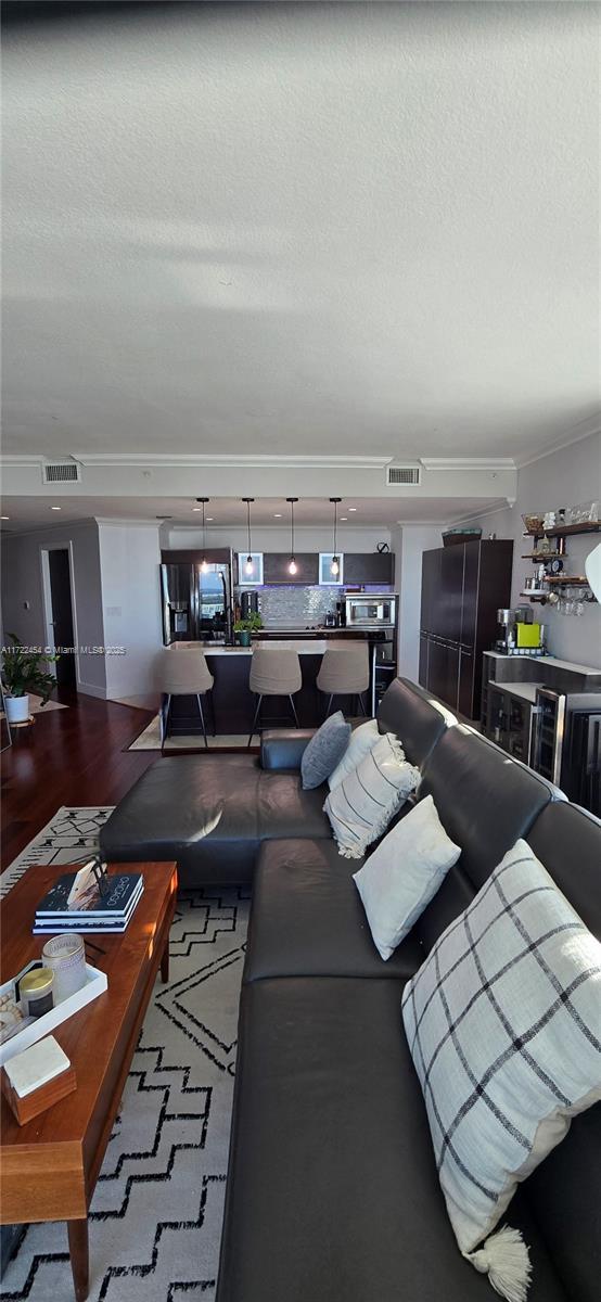 living room featuring hardwood / wood-style flooring, ornamental molding, and a textured ceiling