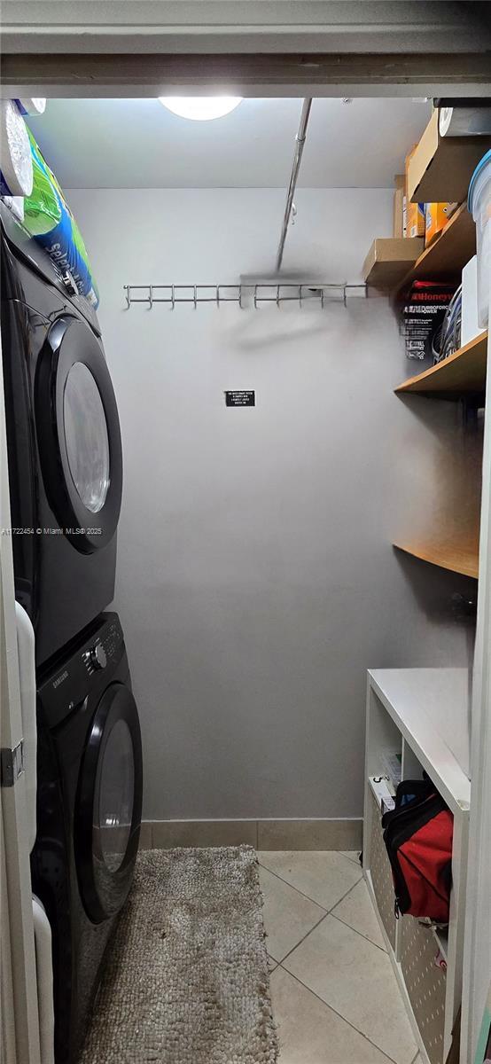 laundry area featuring stacked washing maching and dryer and light tile patterned floors