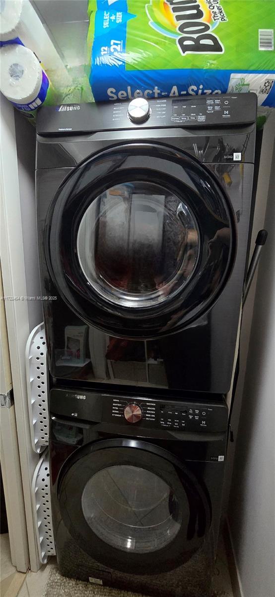 washroom featuring stacked washer and dryer and light tile patterned floors