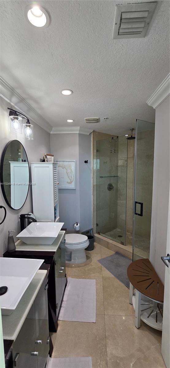 bathroom with toilet, crown molding, a textured ceiling, vanity, and a shower with door