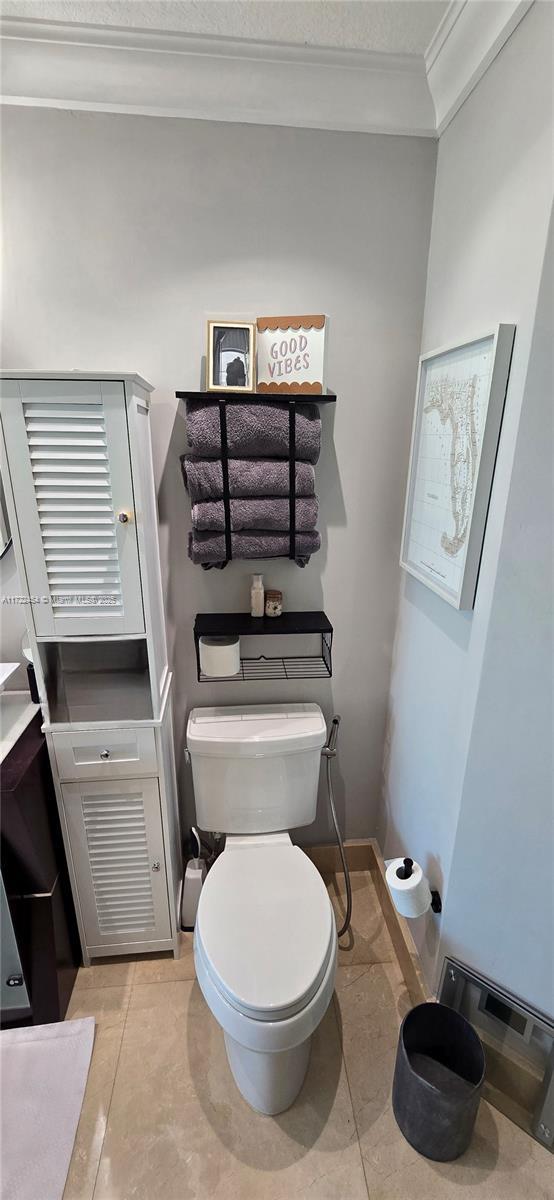 bathroom featuring crown molding and toilet