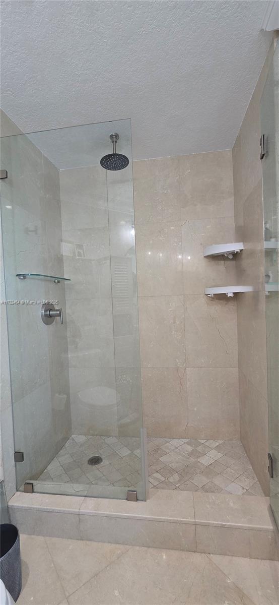 bathroom with walk in shower and a textured ceiling