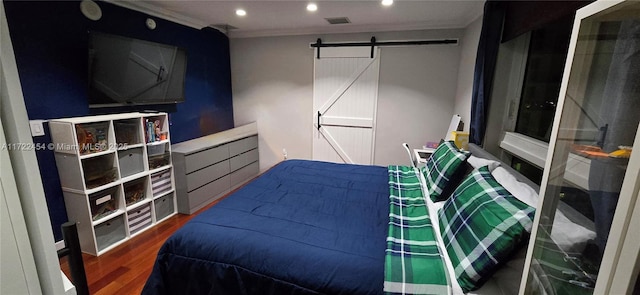 bedroom with hardwood / wood-style flooring, ornamental molding, and a barn door