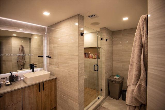 bathroom with vanity, toilet, a shower with door, and tile walls