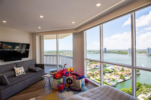 living room featuring a water view, wood-type flooring, and a wall of windows