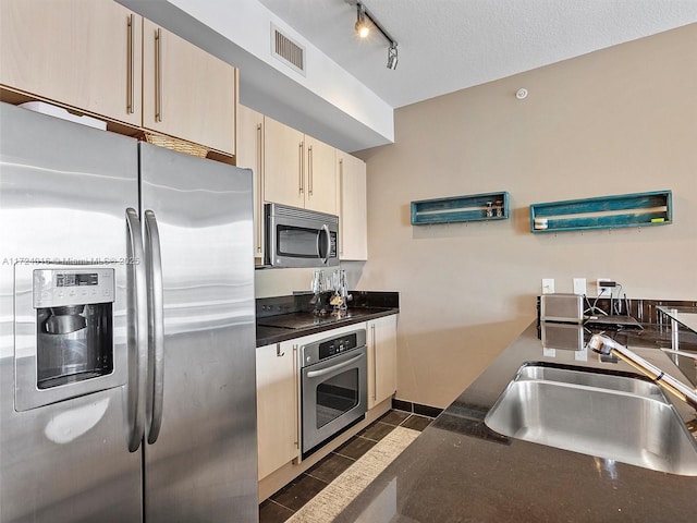 kitchen with appliances with stainless steel finishes, a textured ceiling, cream cabinets, and sink