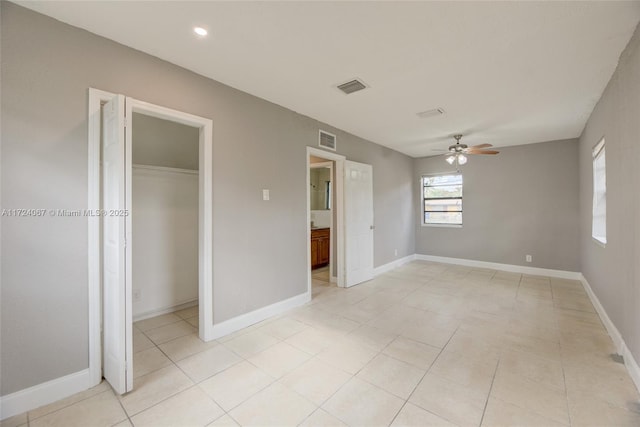 unfurnished bedroom featuring a walk in closet, a closet, and ceiling fan