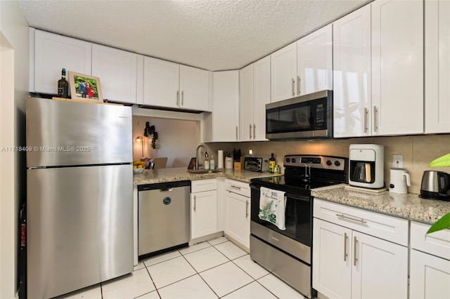 kitchen featuring light tile patterned floors, white cabinetry, appliances with stainless steel finishes, and sink