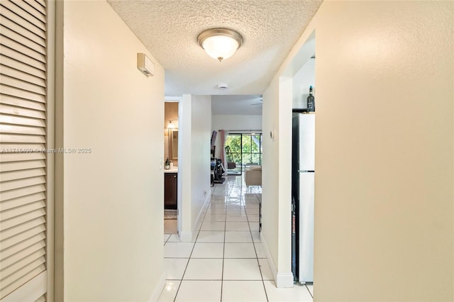 hall featuring a textured ceiling and light tile patterned flooring