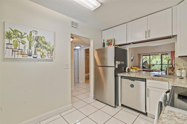 kitchen featuring sink, white cabinetry, appliances with stainless steel finishes, a textured ceiling, and light tile patterned floors