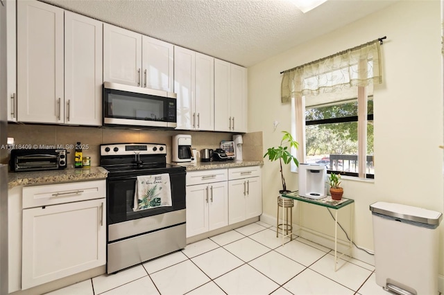 kitchen featuring white cabinetry, stone counters, stainless steel appliances, and a textured ceiling