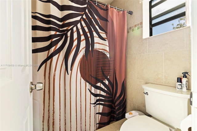 bathroom with toilet, a shower with shower curtain, and tile walls