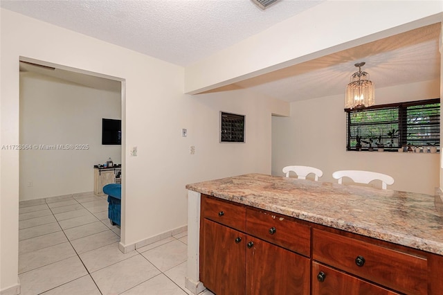 kitchen with light stone counters, a notable chandelier, pendant lighting, a textured ceiling, and light tile patterned floors