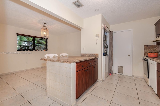 kitchen with hanging light fixtures, range with electric stovetop, light tile patterned floors, kitchen peninsula, and a chandelier